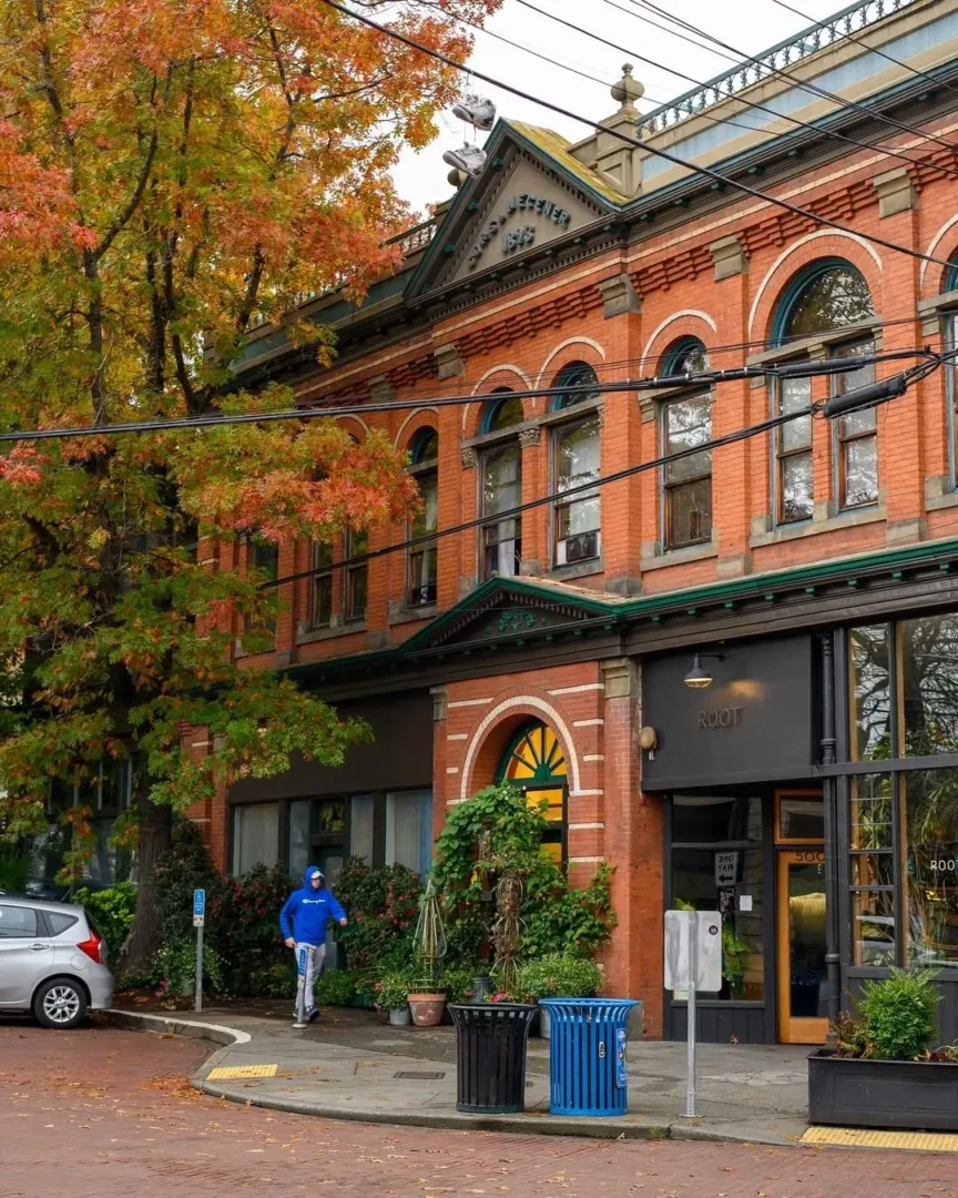 Historic red brick building with arched windows on a tree-lined street in the Ballard Seattle neighborhood.