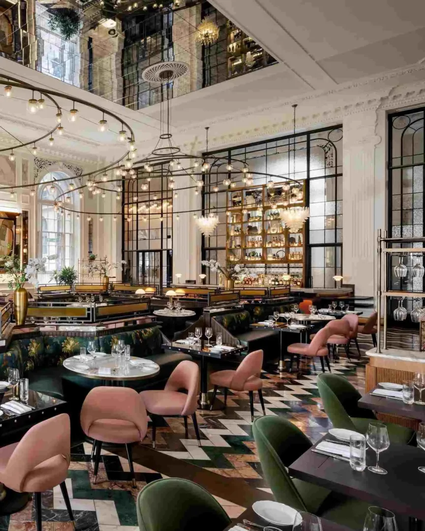 A luxurious, high-ceiling restaurant interior with decorative lights and velvet seating in Seattle in August.