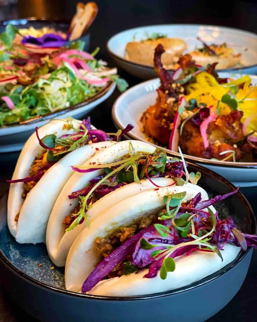 A dark table holds three servings of colorful food, perfect for dining out in Seattle in April.