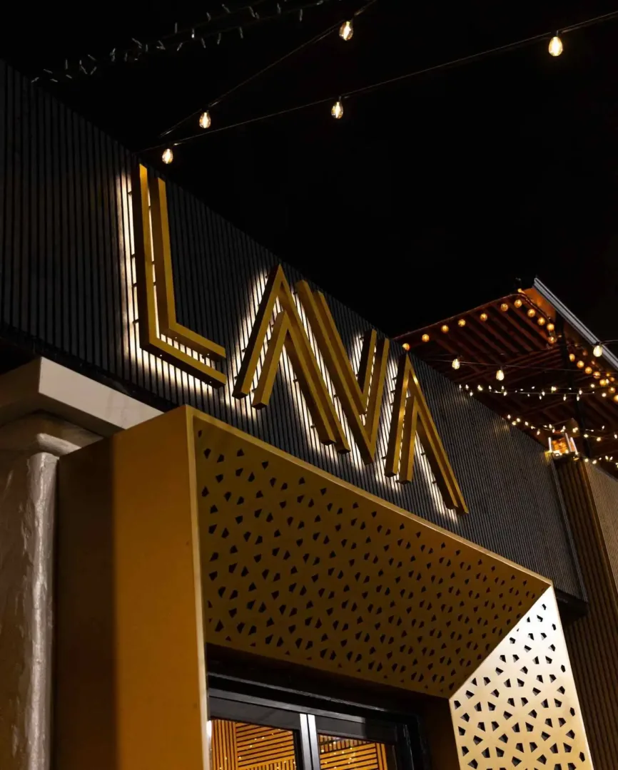 Gold-lit "LAVA" sign on a black building facade at night in Belltown Seattle.