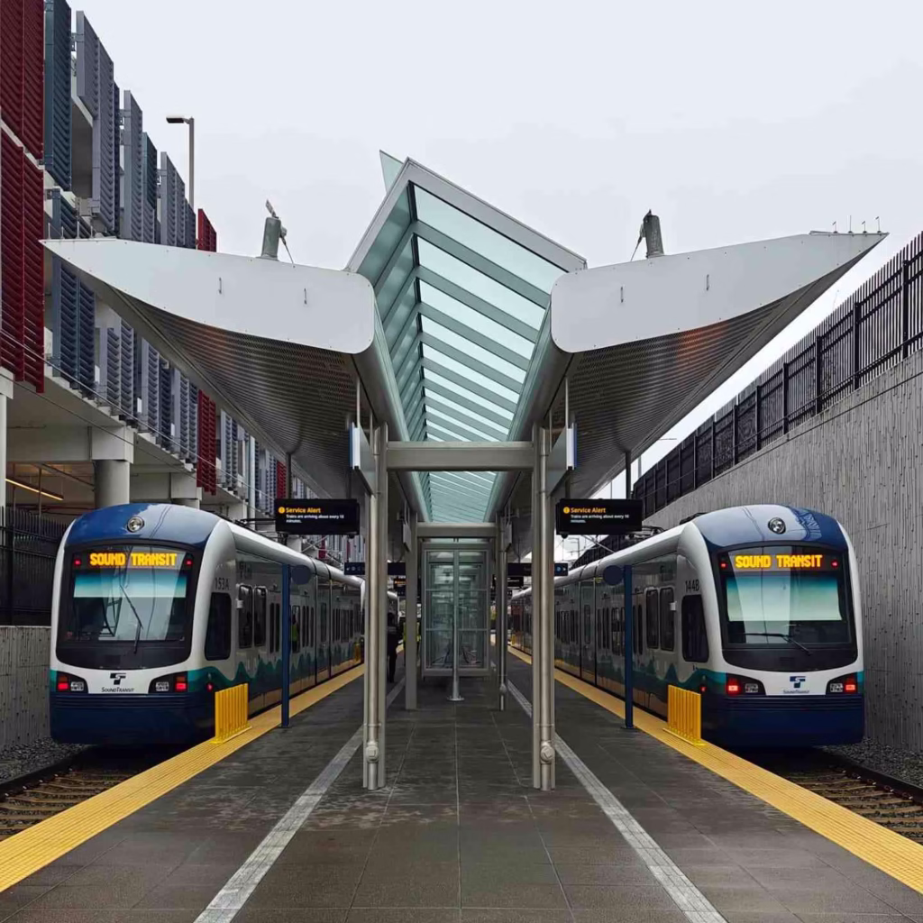 A Seattle Light Rail Guide shows two Sound Transit trains stopped at an outdoor, canopied station platform.