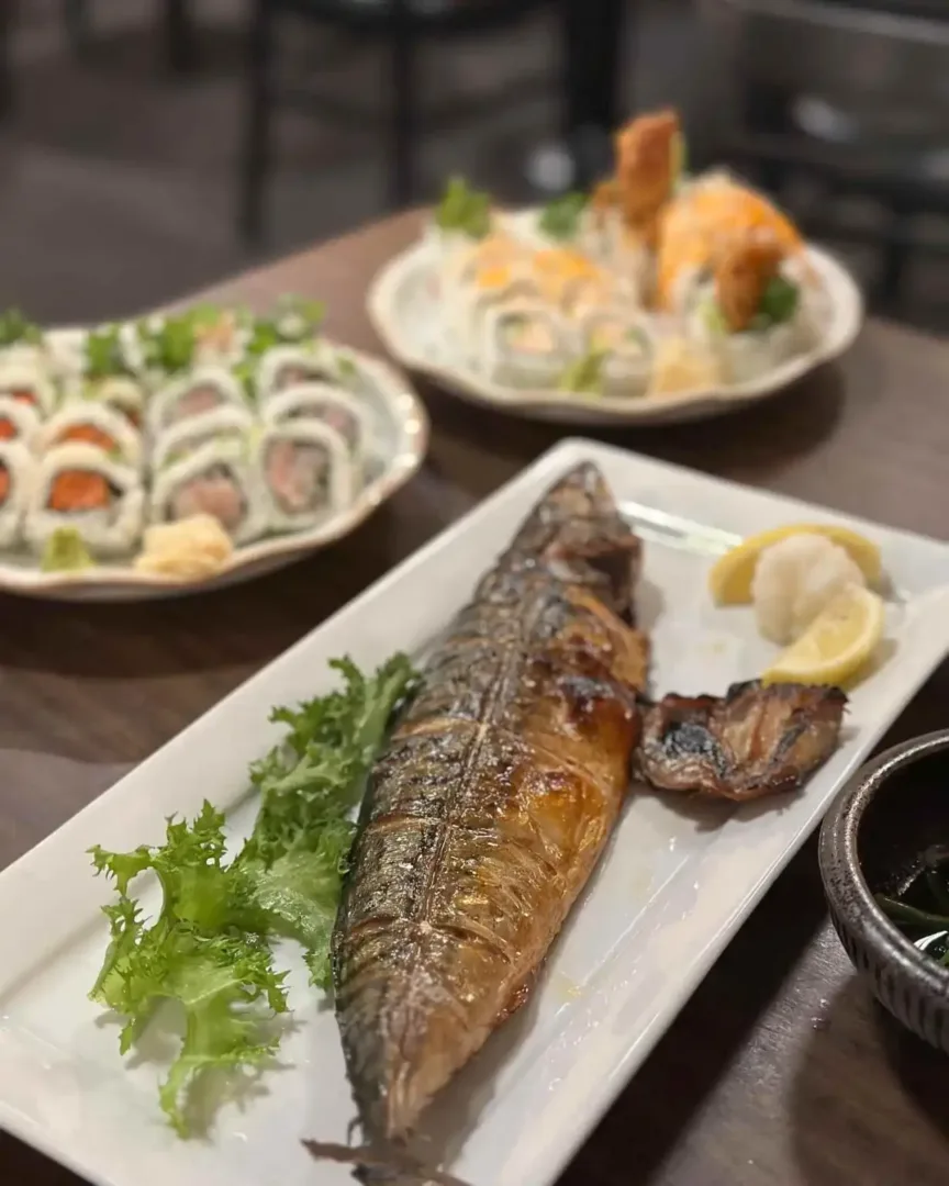 Grilled whole fish and sushi rolls on plates at a restaurant in the International District Seattle.