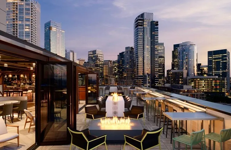 A stylish rooftop bar with fire pits and city skyline views in Seattle in June.