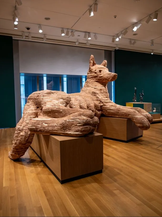 A large wooden sculpture of a reclining dog sits within the modern Capitol Hill Seattle museum.