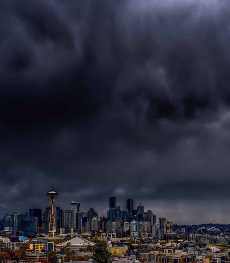 Dark storm clouds loom over the city skyline, complicating getting around Seattle during a rainy afternoon.