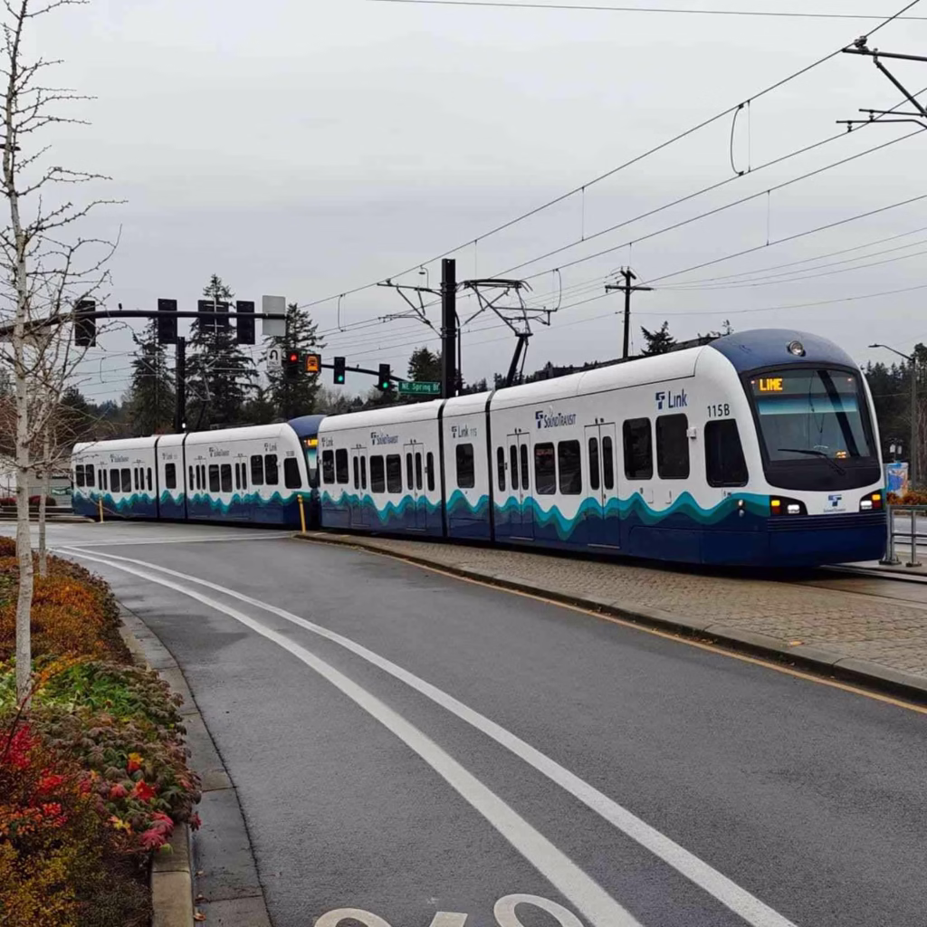 A Seattle Light Rail Guide shows the Link train passing through an intersection on a busy street.