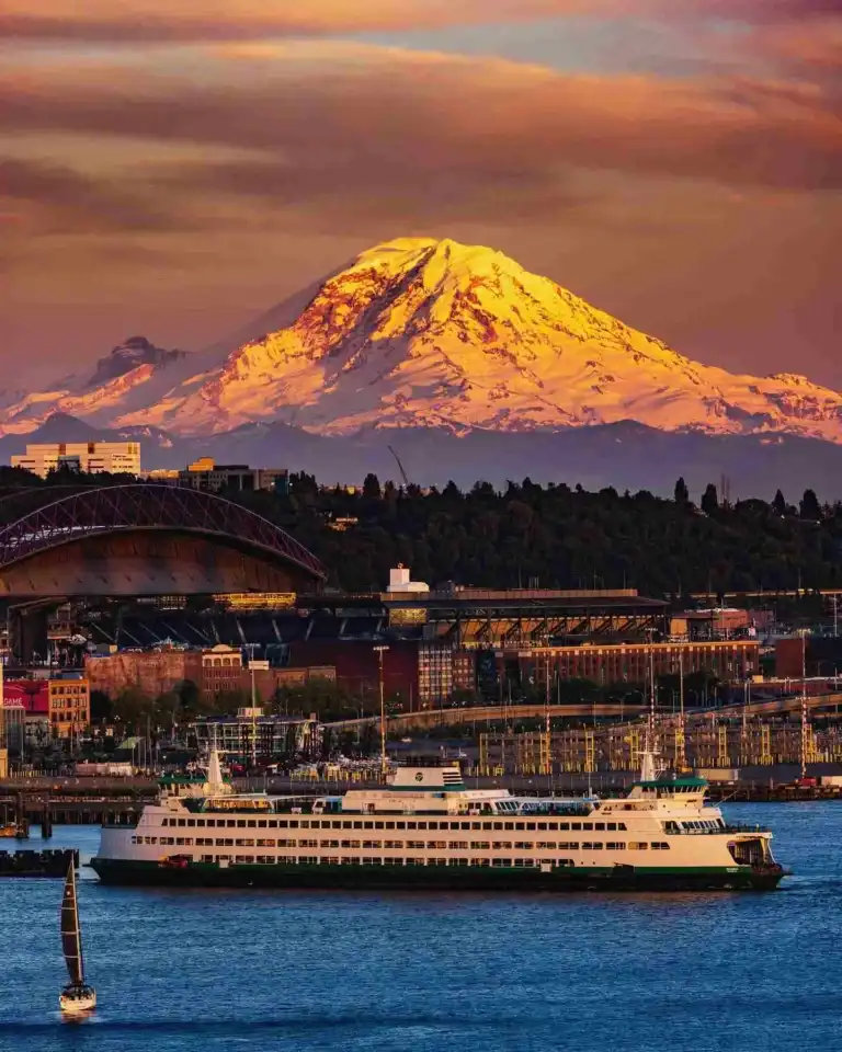 A scenic Bainbridge Island Ferry Seattle route displays a white vessel before a golden Mount Rainier.