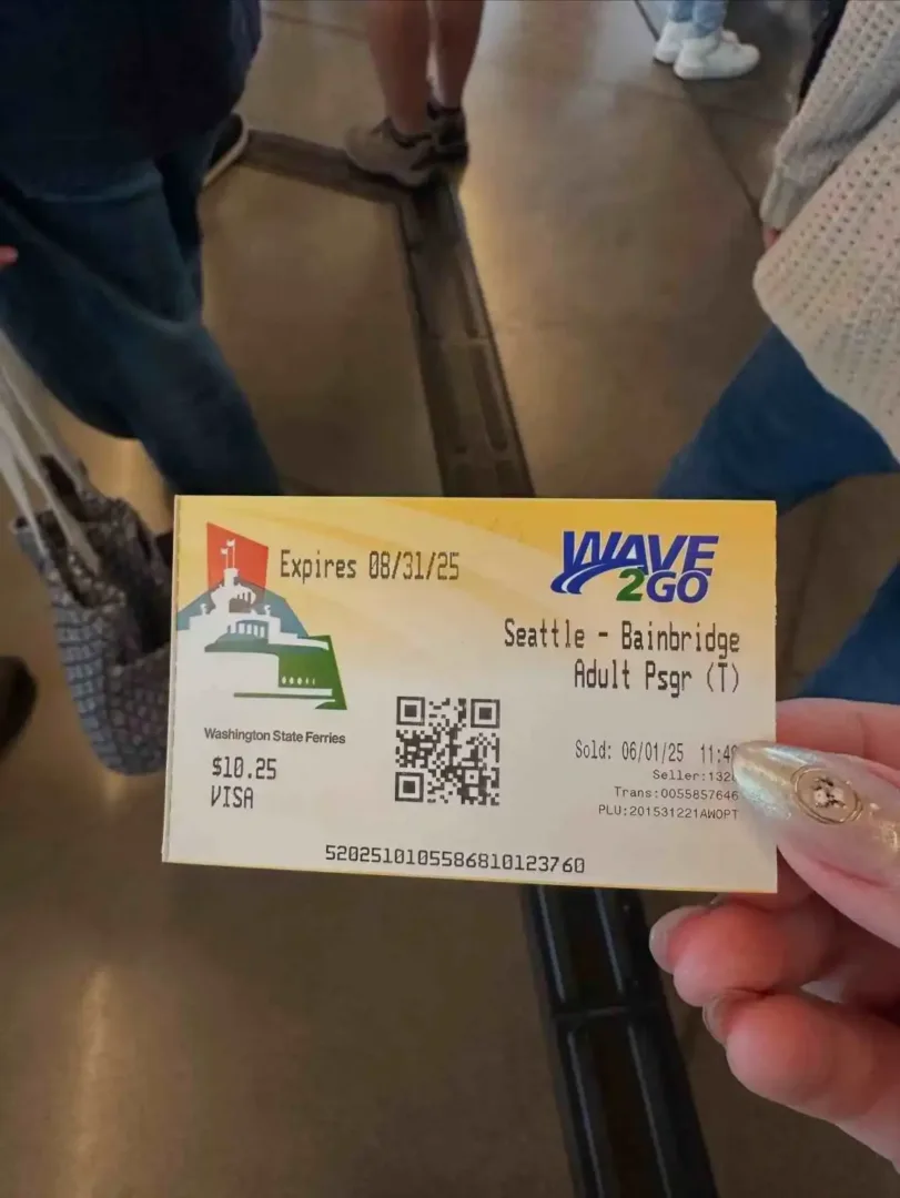 A traveler holds an adult passenger ticket for the scenic Bainbridge Island Ferry Seattle terminal route.