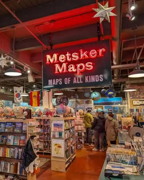 A glowing neon sign hangs above shelves of globes and maps in this downtown Seattle shop.
