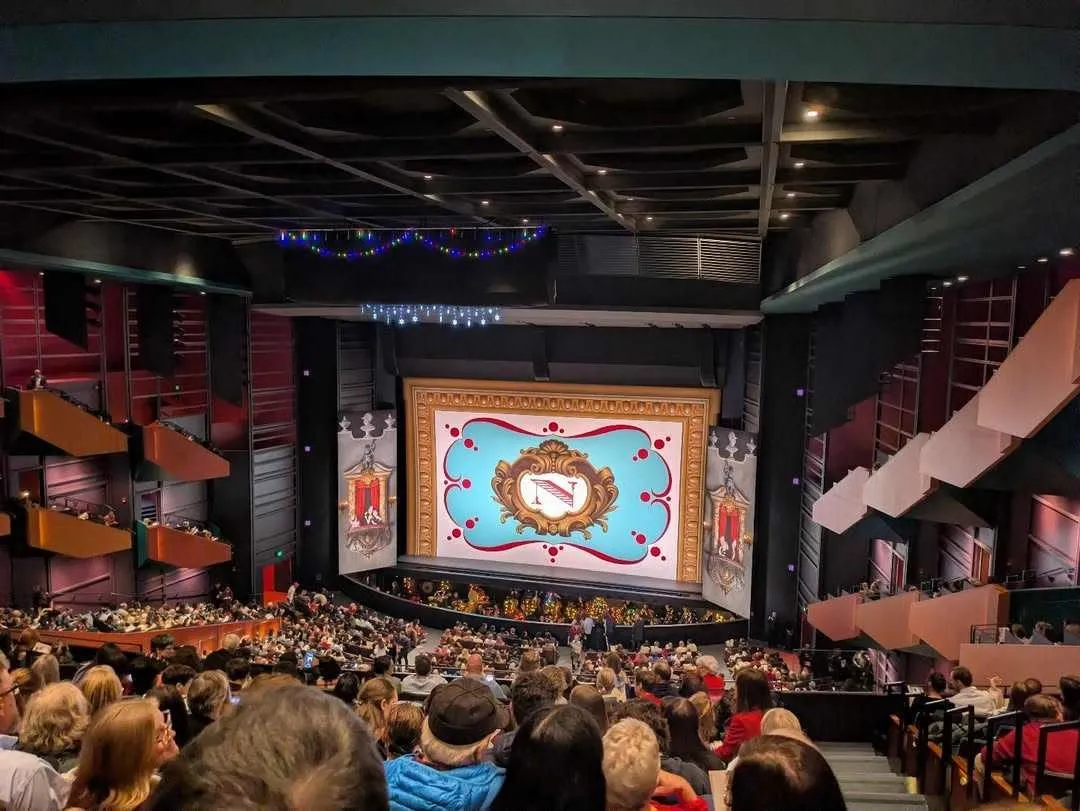 A vibrant audience fills the venue for a performance featured in the Seattle Theater Guide.