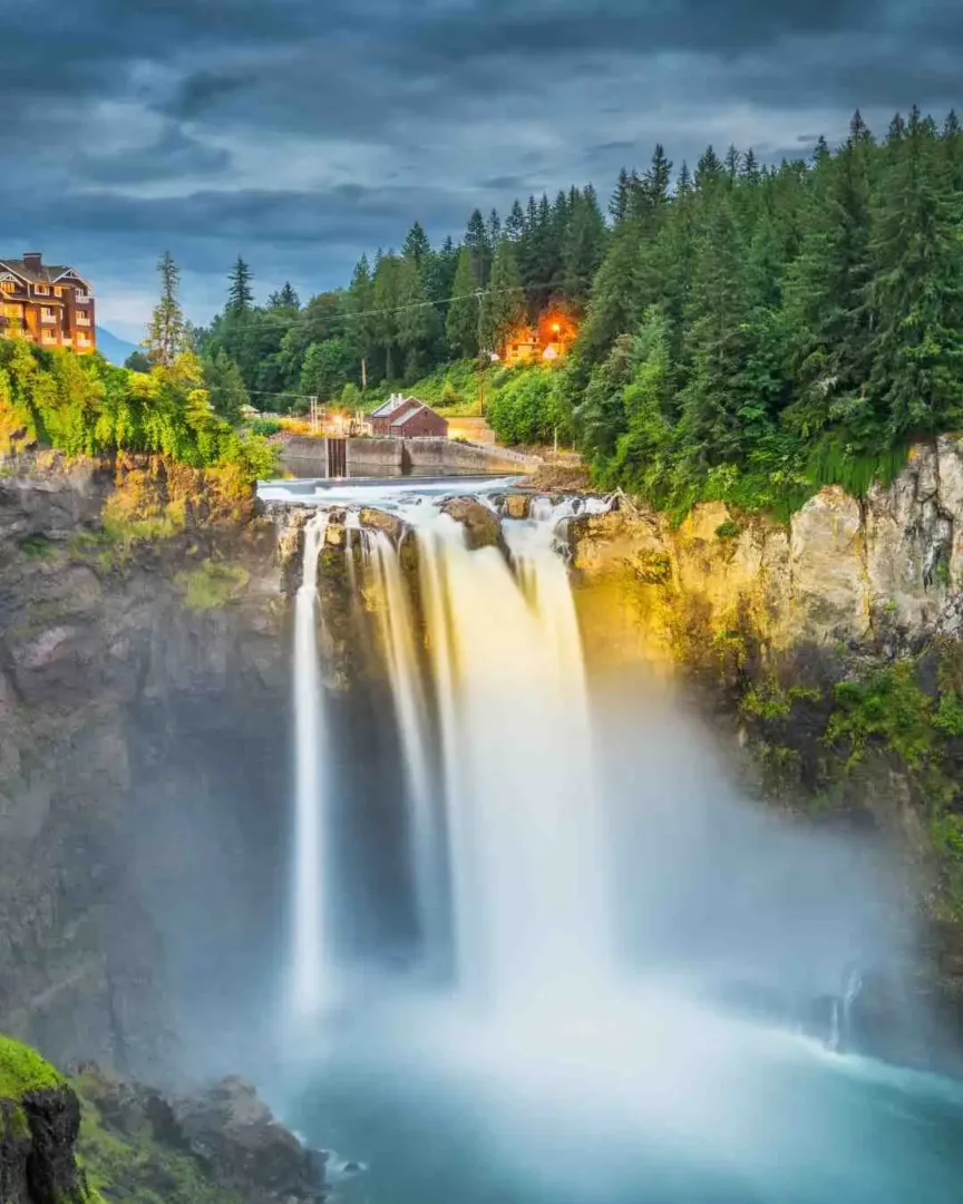 A vibrant waterfall cascades into a misty basin during a scenic Snoqualmie Falls Tour at dusk.